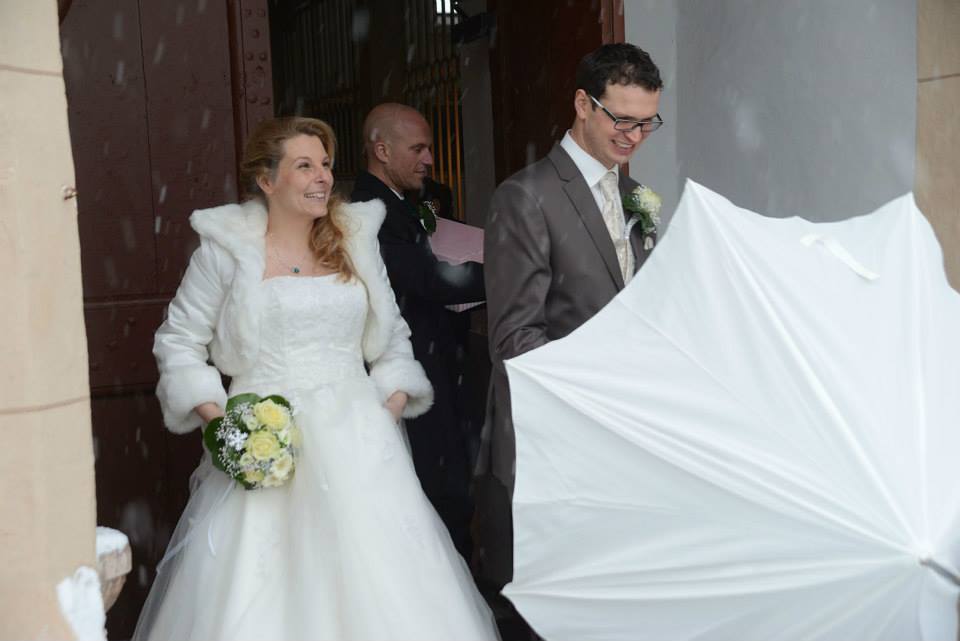 Brautpaar tritt im Schneegestöber aus Kirche