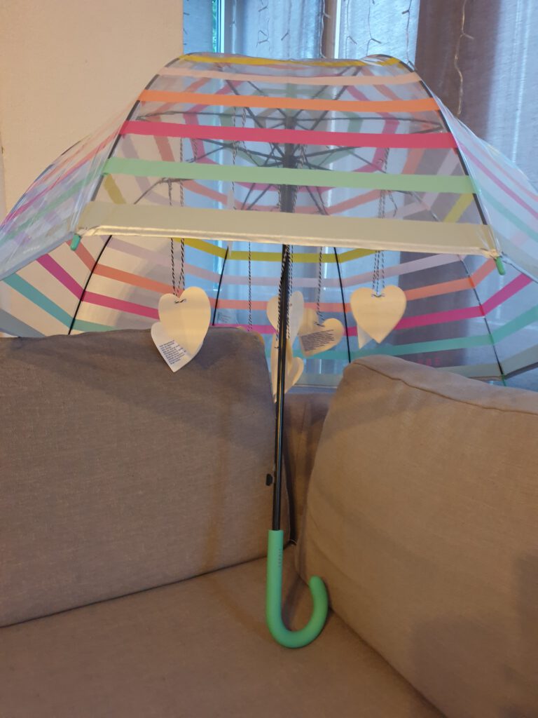Regenschirm mit Pappherzen, auf denen Wünsche für eine Lehrkraft stehen, die versetzt wurde